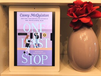 One Last Stop book cover showing on an ipad next to a vase holding a red rose